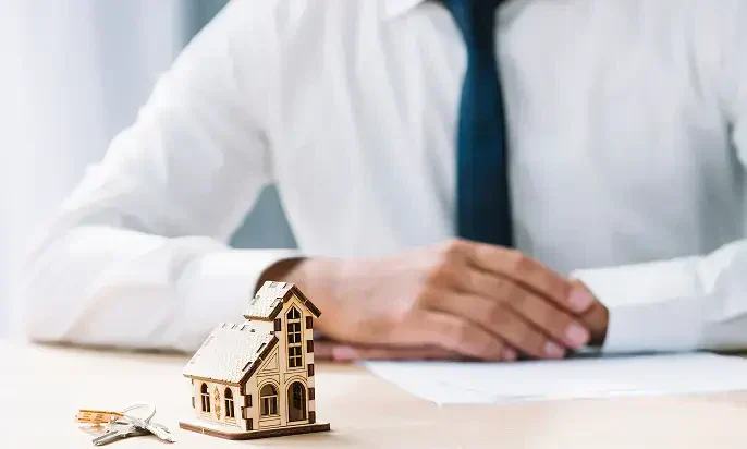 A business meeting in a bright room, focusing on documents and plans, with a laptop, glasses of water, and discussions underway.
